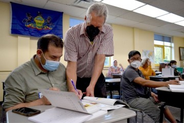 A volunteer helps a student learn English